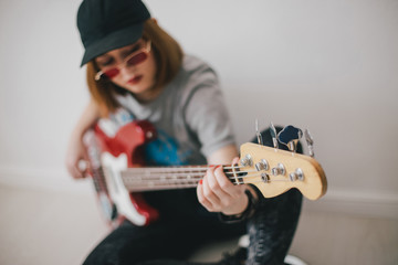 Young beautiful woman posing with red bass guitar in a studio
