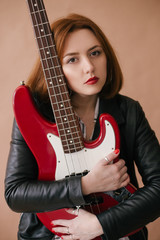 Young beautiful woman posing with red bass guitar in a studio