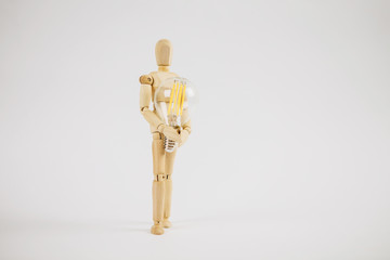 Wooden puppet with light bulb in white background.Wooden mannequin figure taking the first step  to his goal- career, growth or development concept.