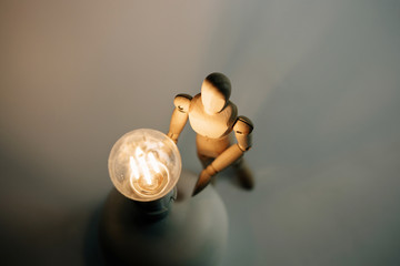 Plakat Wooden puppet with light bulb in white background.Wooden mannequin figure taking the first step to his goal- career, growth or development concept.