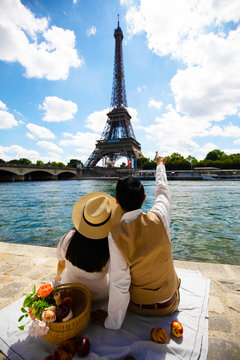 Young couple is travel in Paris and looking at eiffle tower at river side as for pre-wedding photograph.