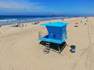 Aerial view Lifeguard tower on the Huntington Beach with people enjoying the beach during sunny day. Southeast Los Angeles, California. 