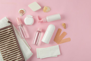 A set of cosmetics and personal care products for travel in a cosmetic bag on a light pink background. top view. travel cosmetics