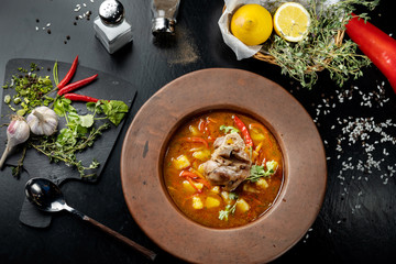 Soup with pepper, potatoes and bone with meat.
