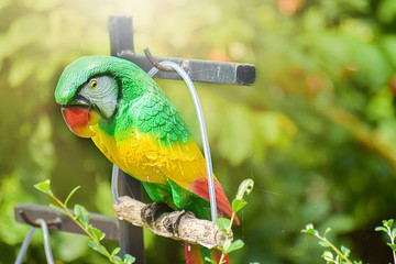Colorful of ceramic parrot hanging on the iron rail in garden