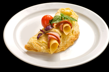 Egg omelette with ham and cheese, decorated with cherry tomatoes and basil, closeup.