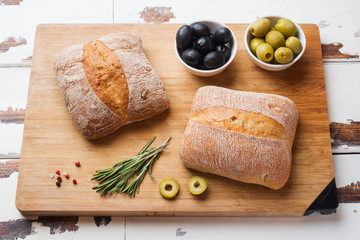 Italian ciabatta bread with olives and rosemary on a wooden Board.