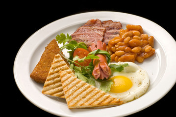 English breakfast: fried egg, bacon, beans and toast on a plate close-up.