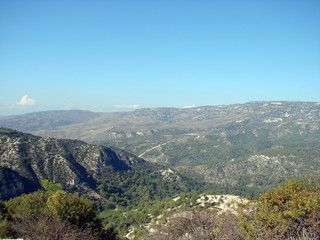 The landscape from the top of a mountain of endless mountain ranges covered with green forest on the background of a clean, blue, morning sky on the horizon.