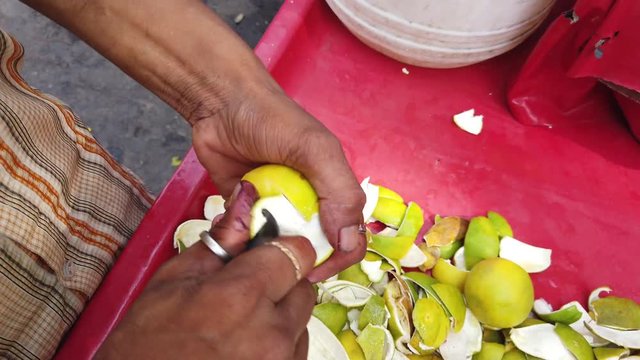 Street food- Fresh fruits juice being sold and served of sweet lemon or mausami, orange or santra, anaar or pomegranate by vendor cart in the hot weather. 4k slow-motion close-up stabilized handheld