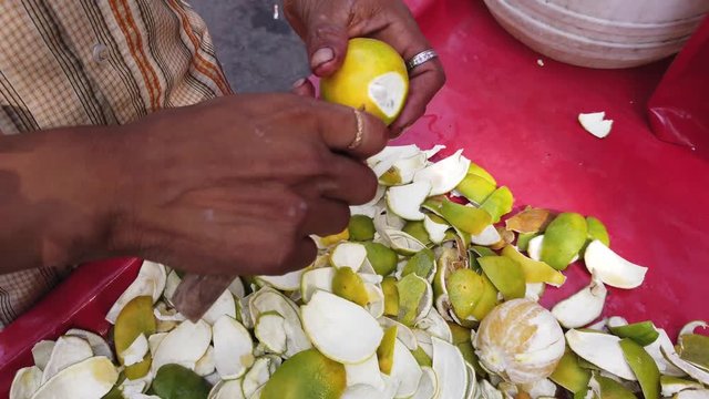 Street food- Fresh fruits juice being sold and served of sweet lemon or mausami, orange or santra, anaar or pomegranate by vendor cart in the hot weather. 4k slow-motion close-up stabilized handheld