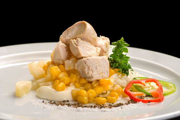 Chicken meat with corn, bell pepper, mayonnaise and sauces on a white plate.