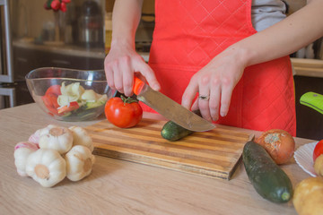 Obraz na płótnie Canvas woman cooking healthy meal in the kitchen. Cooking healthy food at home. Woman in kitchen preparing vegetables. Chef cuts the vegetables into a meal