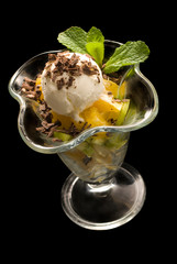 Delicious ice cream with fruits and mint. Isolated on black.