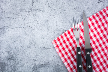 Fototapeta na wymiar knife and fork at napkin on wooden background
