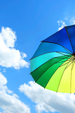 colorful umbrella on blue sky background. weather concept. summer season. umbrella against cloudy blue sky. copy space. soft focus