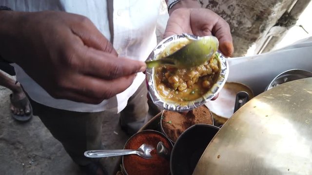 Street food- Chole Kulche- popular fast meal with dry chickpeas spicy masala mixture with maida based bread Kulcha in India, Pakistan and Bangladesh.  4k slow-motion close-up stabilized handheld 