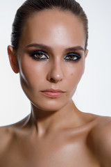 Fototapeta premium Portrait of a sexy woman with wet black hair. Professional smoky makeup. Long hair combed up. Look into the camera, brown eyes, close-up on white isolated background