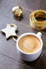 A cup of coffee and a small Christmas Star on wooden background. 