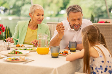 Grandparents talking to their lovely girl and eating breakfast