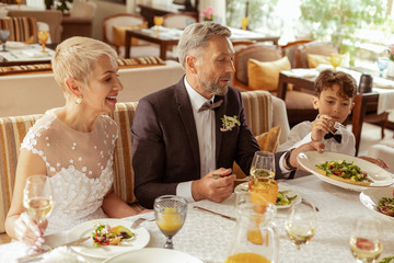 Aged bride sitting near husband while celebrating wedding