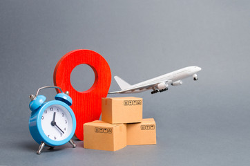 Airplane and stack of cardboard boxes, red position pin and blue alarm clock. concept of air cargo...