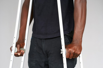 Hand african man on crutches on a gray background. Close-up man walking with crutches.