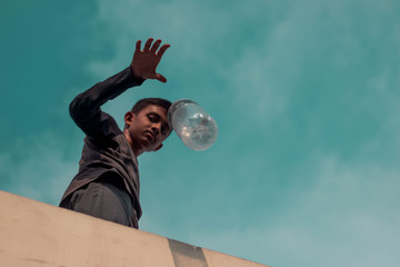 Young boy is throwing plastic bottle