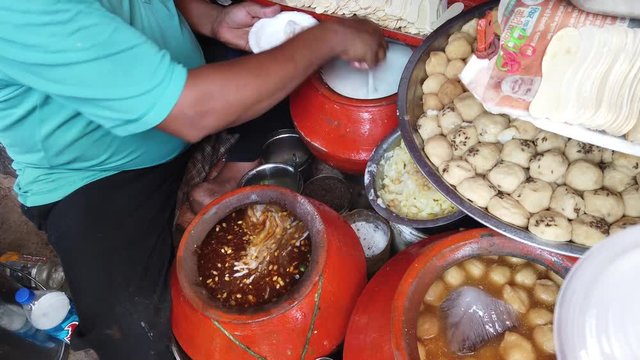 Street food- Dahi bhalla and Papri chaat, soaking vadas in thick curd, popular traditional fast food using crisp fried dough wafers in India and Pakistan. 4k 60fps close-up stabilized handheld 