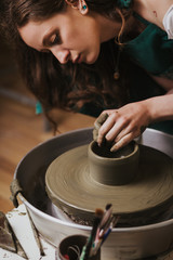 Artisan woman working on pottery wheel and making a pot.