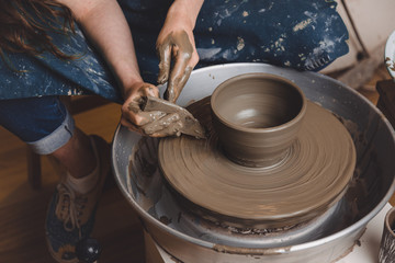 Woman hands working on pottery wheel and making a pot. Concept of crafting.