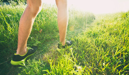 One young man is jogging cross-country through the pathway in the meadow