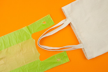 Flat lay photo of green plastic bag compare to fabric tote bag on orange background as eco-friendly and sustainable lifestyles concept