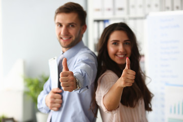 Businessman and business woman hold thumbs up