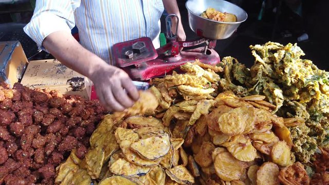 Street food- Various fried pakora with paneer, aloo, pyaaz, bread and mirchi, and Samosa being cooked and served  with chaat and chutneys by vendor cart India. 4k 60fps close-up stabilized handheld