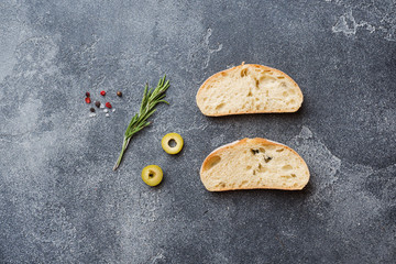 Italian ciabatta bread with olives and rosemary on a Dark concrete background. Copy space