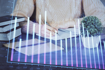 Forex graph on hand taking notes background. Concept of research. Double exposure