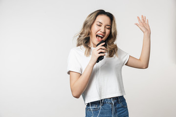 Woman posing isolated over white wall background singing listening music with earphones and mobile phone.