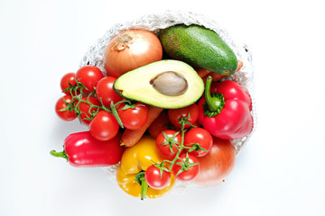Bunch of mixed organic fruit, vegetables: carrot, tomato, paprika pepper, eggplant, avocado and apples in reusable cotton bag. Zero waste concept. Background, copy space, close up, flat lay.
