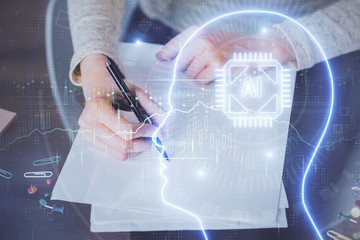 Double exposure of writing hand on background with brain hologram. Concept of learning.