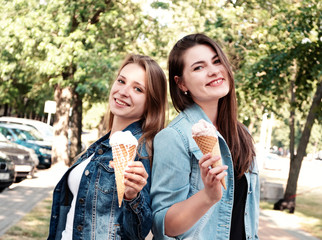 Two girls in summer on street eat ice cream. Girlfriends, weekend in city.