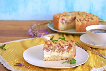 Dessert, sliced shortcrust cake with rhubarb and cottage cheese or ricotta on a white plate.