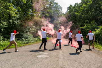 red ultras fans with torches and smokes make an ambush on the street. hooligans with red head masks...