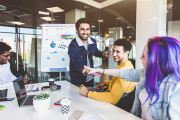 Obraz premium Group of multi ethnic executives discussing during a meeting. Business man and woman sitting around table at office and smiling. A team of young creative designers