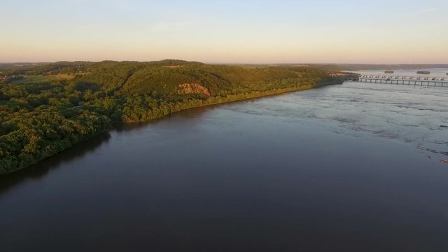 Aerial ascending shot during the sunset of the Susquehanna river with a long bridge in the horizon.