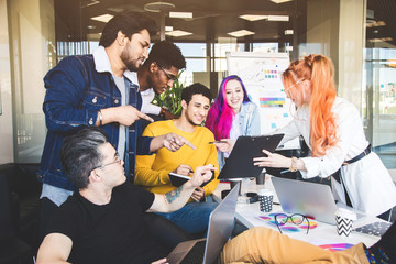 Group of multi ethnic executives discussing during a meeting. Business man and woman sitting around table at office and smiling. A team of young creative designers