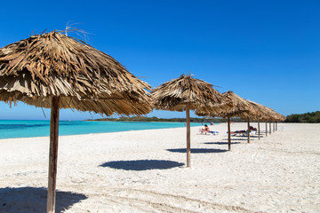 Sun umbrellas on the beach of palm leaves. Horizontally.
