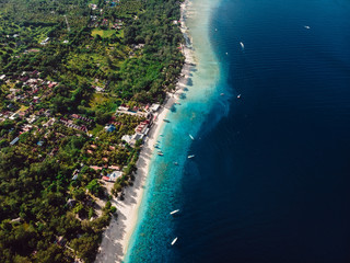 Tropical island with beach, boats and turquoise ocean. Aerial view.