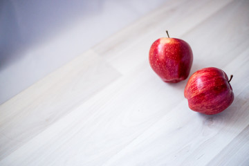 two red apples on a wooden board