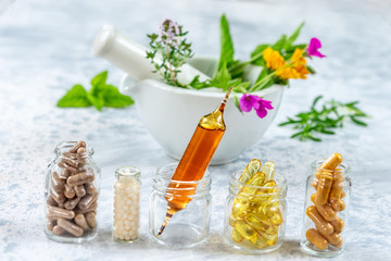 Herbal supplements and vitamins on wooden tray , decorated with colorfull medicinal flowers and herbs blurry wooden background © JPC-PROD